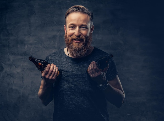 Emotionele, grappige roodharige bebaarde dronken hipster-man houdt ambachtelijk gebotteld bier vast.