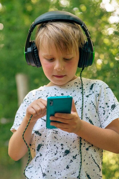 Emotionele jongen 9 jaar oud in het bos met koptelefoon luisteren naar muziek