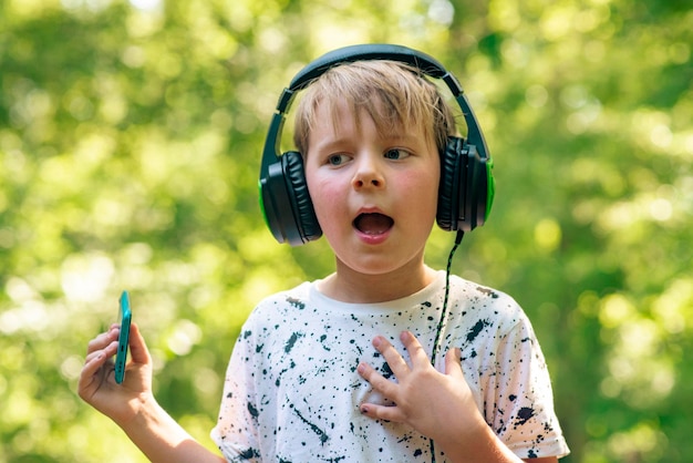 Foto emotionele jongen 9 jaar oud in het bos met koptelefoon luisteren naar muziek