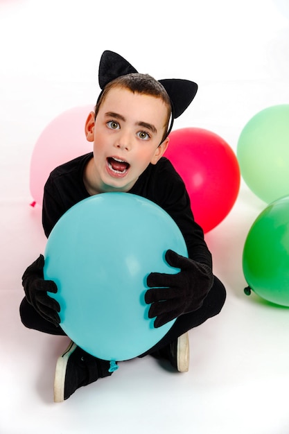 Emotionele jongen gekleed als een zwarte kat met een blauwe ballon geïsoleerd Purim Halloween