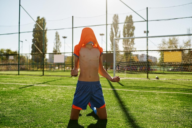 Emotionele jongensvoetballer met t-shirt op hoofd blij doel of overwinning