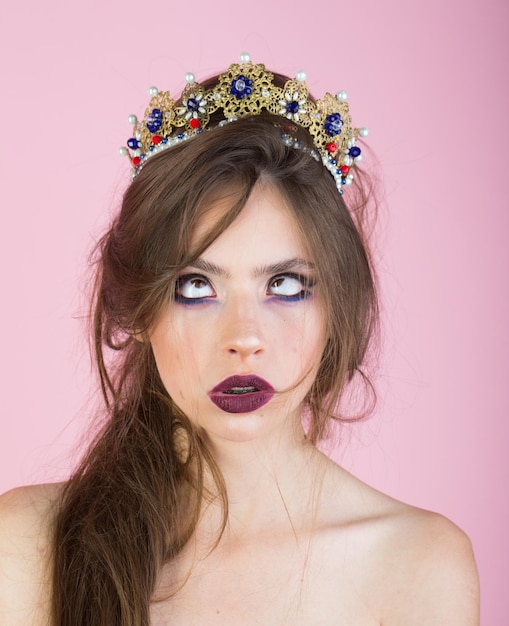 Emotionele koningin met gek gezicht en modieuze make-up in kroon Verrast koningin met trendy make-up