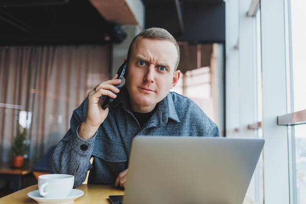 Emotionele man die webdesign bestudeert tijdens e-learning op afstand op laptop voor online onderzoek verbinding maken met wifi op netbook werk freelancen telefoongesprek