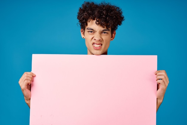 Emotionele man met roze poster mockup blauwe achtergrond Hoogwaardige foto