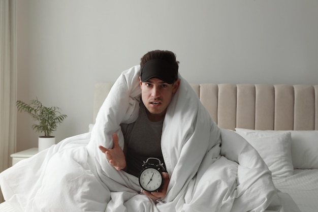 Emotionele man met wekker in bed Te laat komen vanwege verslapen