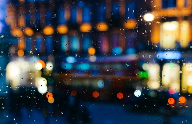 Emotionele melancholische abstracte achtergrond met intreepupil lichten bokeh in Londen Uk achter regendruppels in vensterglas Focus op enkele druppels vanwege de ondiepe scherptediepte