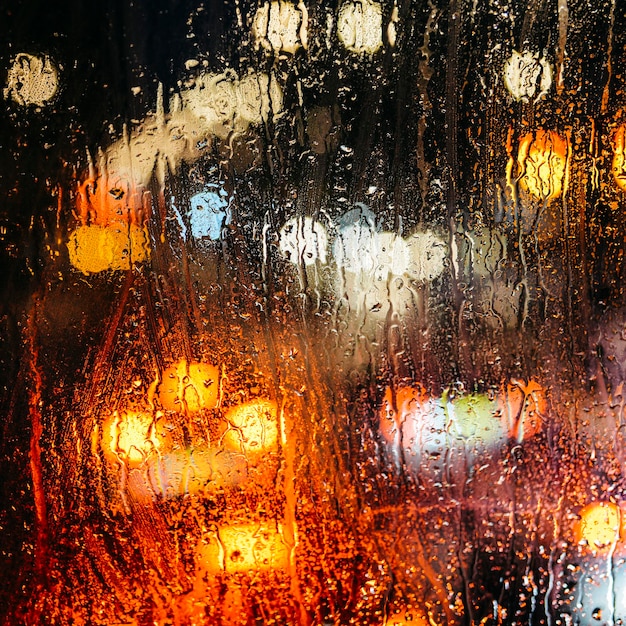 Emotionele melancholische abstracte achtergrond met intreepupil lichten bokeh in Londen Uk achter regendruppels in vensterglas Focus op enkele druppels vanwege de ondiepe scherptediepte