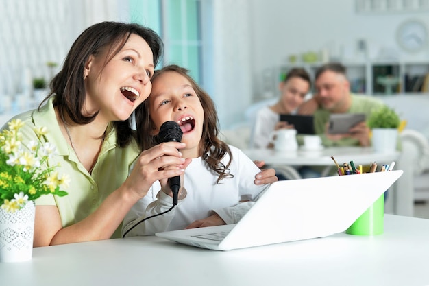 Emotionele moeder en dochter zingen karaoke met laptop thuis