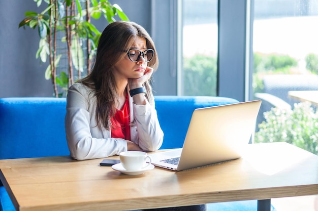 Emotionele werkneemster die op kantoor zit met haar laptop