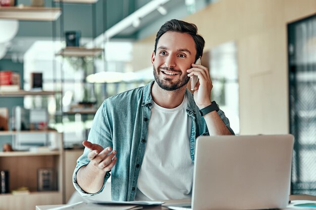 Emotionele zakenman met conversie op smartphone Man aan het werk op laptopcomputer in café