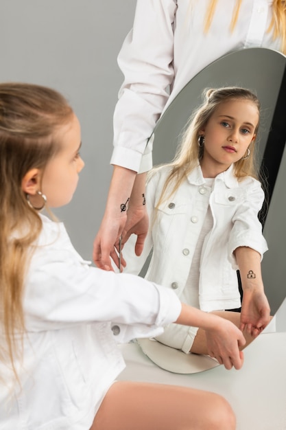  Emotionless young kid observing picture on her hand in mirror reflection