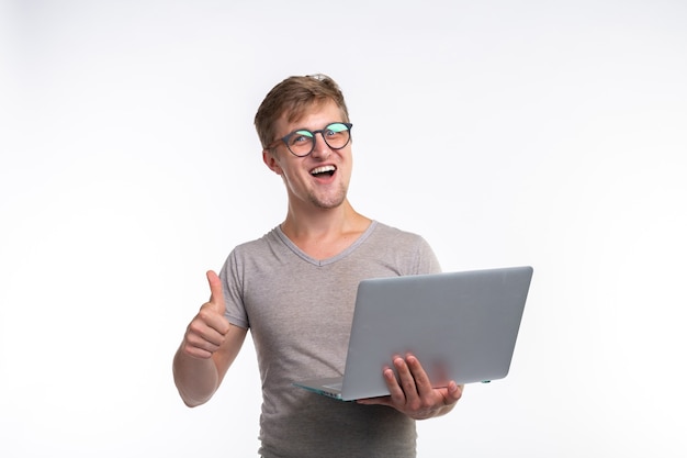 Emozioni, educazione e concetto di persone. un giovane uomo bello che guarda nel computer portatile e ride.