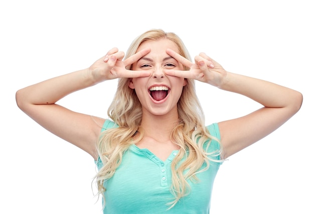 emotions, expressions, positive gesture and people concept - smiling young woman or teenage girl showing peace hand sign with both hands