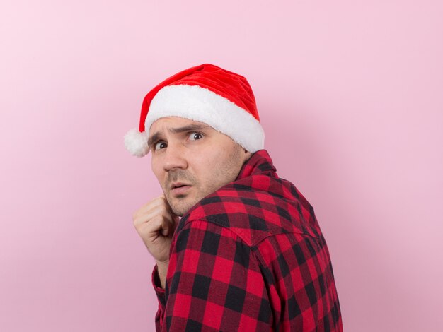 Emotions on the face, fear, holiday memories, negative. A man in a plaid rabbit and a Christmas red hat