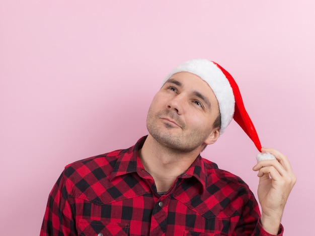 Emotions on the face, pensive, reflection, plan, idea. A man in a plaid rabbit and a Christmas red hat