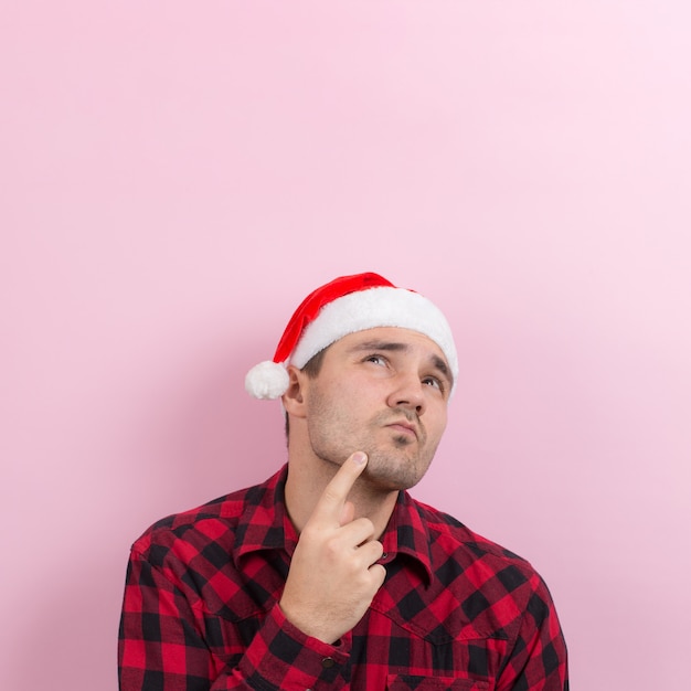 Emotions on the face, pensive, reflection, plan, idea. A man in a plaid rabbit and a Christmas red hat