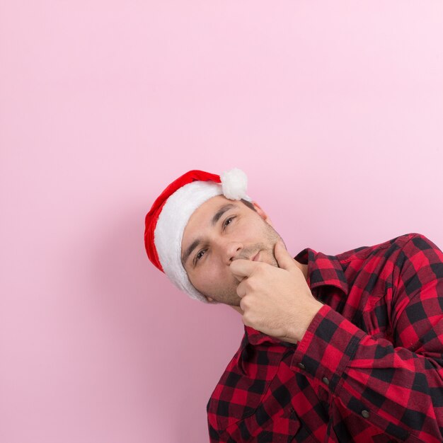 Emotions on the face, pensive, reflection, plan, idea. A man in a plaid rabbit and a Christmas red hat