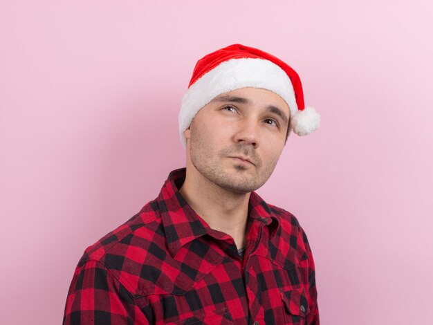 Emotions on the face, pensive, reflection, plan, idea. A man in a plaid rabbit and a Christmas red hat