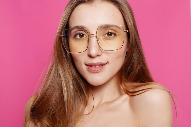 Emotions fashion people youth and beauty concept close up shot of stylish young woman in sunglasses smiling against pink background beautiful female model with copy space