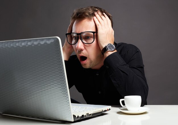 Photo emotions man sitting at a computer funny boy in glasses