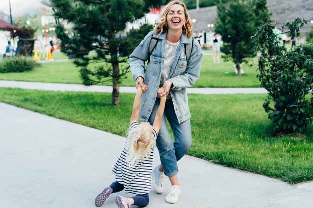 Photo emotions of a mom fooling around with a little daughter mom twirling her daughter outside