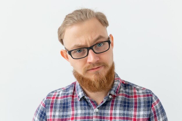 Emotions and people concept - Portrait of serious man with red beard on white surface