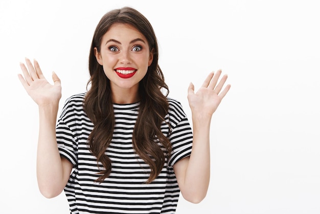 Photo emotive surprised happy young girl cheering, raise hands joyful and enthusiastic, smiling applause, clasping hands entertained