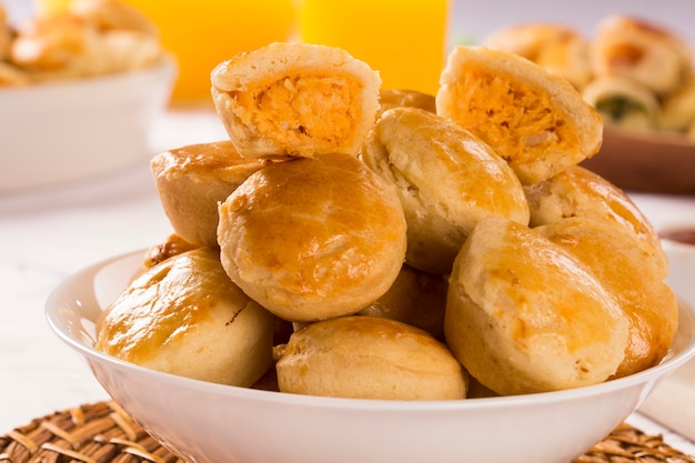 Empada Brazilian snack. pie with chicken on white plate on wooden background