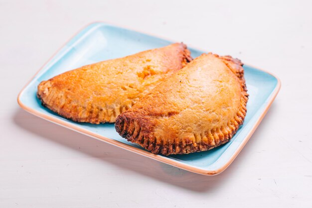 Empanada, meat pie on a plate and white surface