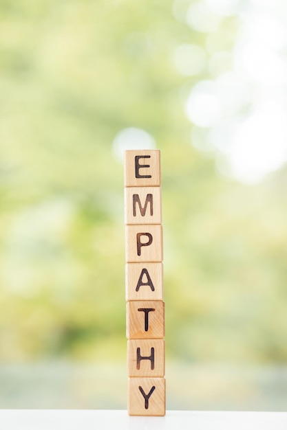 Empathy word is written on wooden cubes on a green summer background Closeup of wooden elements