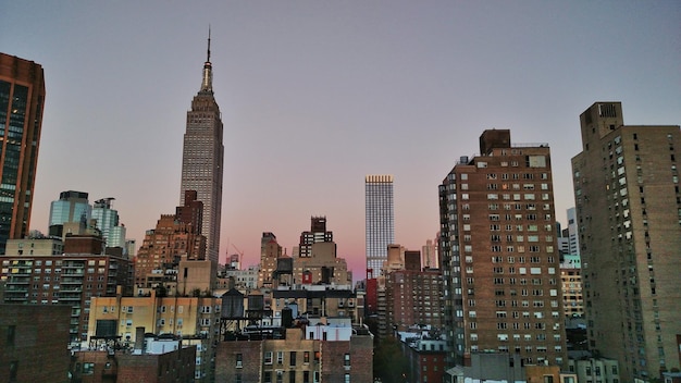empire state building in city against clear sky at dusk