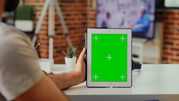 Employee analyzing greenscreen on modern tablet at home,
holding digital device with isolated chroma key copyspace template.
looking at blank mockup background on portable gadget.