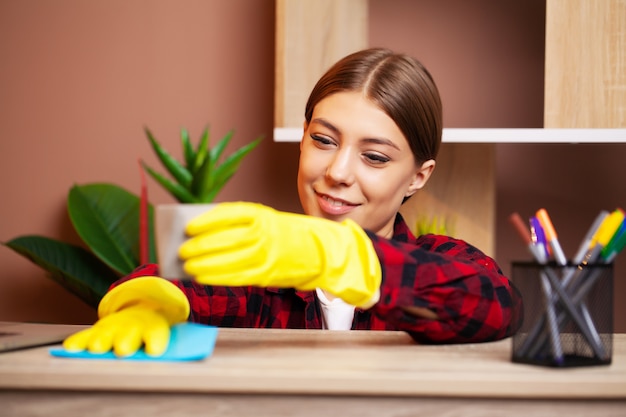 Employee of a cleaning company in overalls and yellow gloves cleans the office