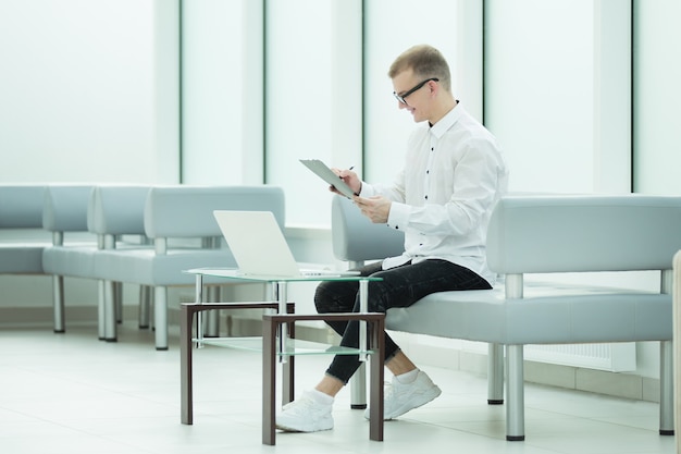 Employee of the company reads a business document sitting in the office lobby. photo with copy spac