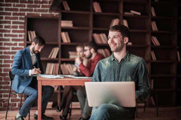 Employee of the company sits on a chair with laptop on the backg