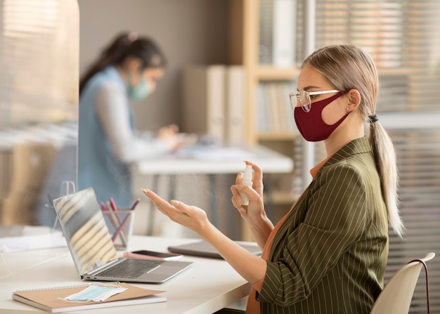 Foto dipendente che disinfetta le mani al lavoro