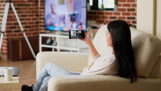 Photo employee doing remote work while in digital videoconference meeting on smartphone. young adult person working from home while discussing with colleagues on virtual video call conference.