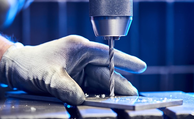 ベンチドリルでアルミニウム平鋼板を掘削する従業員金属ドリルビットは、産業機械の鋼ビレットに穴を開けます金属加工産業クローズアップ