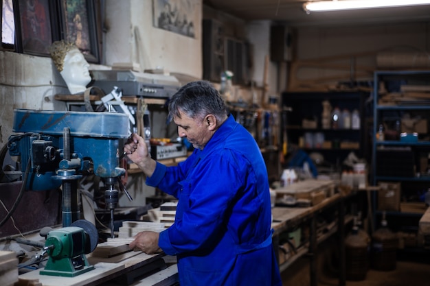 Employee drills the item in the workshop with the help of a drilling press