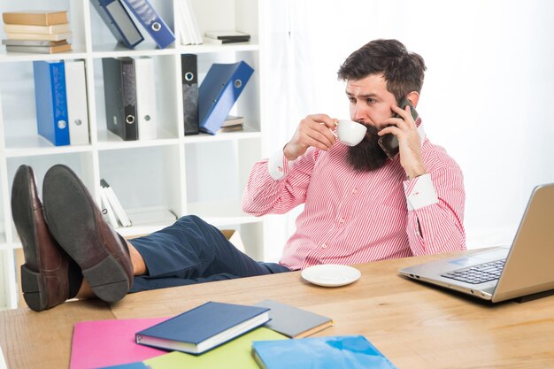 Photo employee drink cup of tea talking on mobile phone in modern office technology