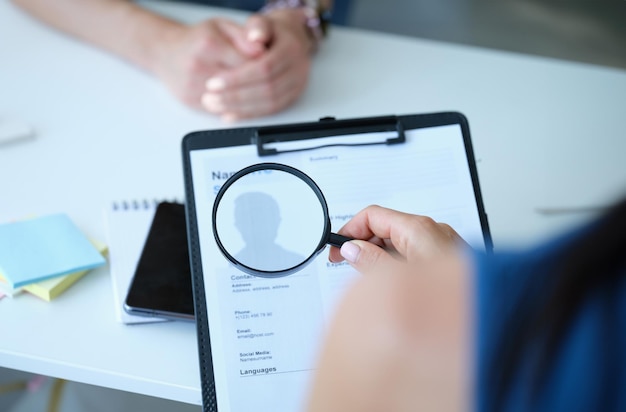 employee examines resume application form under magnifying glass