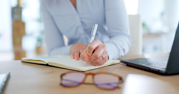 Foto le mani dei dipendenti scrivono appunti nel diario con il portatile da scrivania e l'agenda del programma aziendale o il promemoria amministrativo. notebook da ufficio e donna che pianificano nel diario con revisione o ricerca di idee