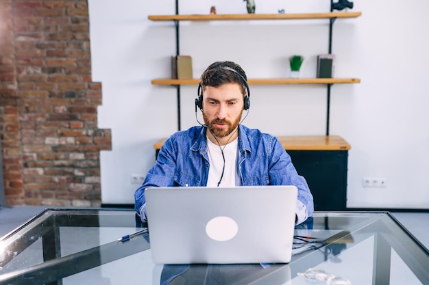 An employee in headphones speaks with a client online using the wireless Internet on a laptop