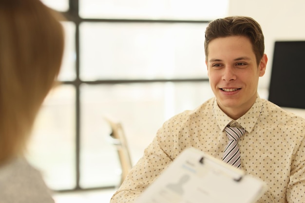 Employee holds blank form against man boss smiling in company office female applicant examines