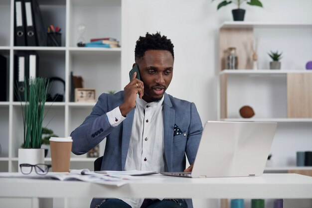 Employee making business call focused on laptop at his workplace. Black businessman consulting customer, discussing financial report. Contract negotiation and discussion concept