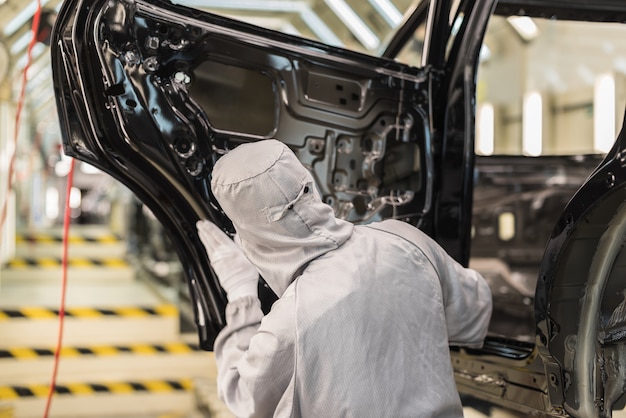 an employee of the paint shop of an automobile plant checks the quality of the painted surface