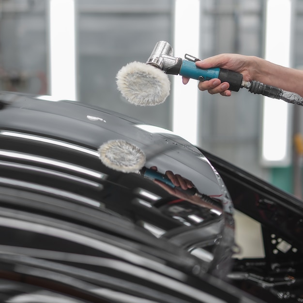 An employee polishes the painted surface of the car