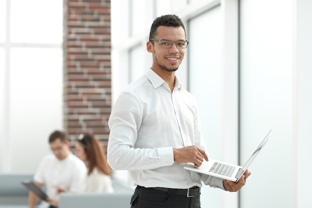 Employee typing on a laptop standing in the office.