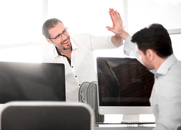 Employees give each other a high five over the computer desk