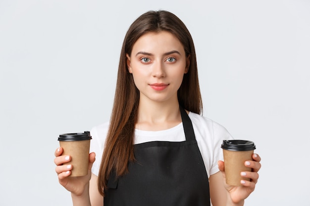 Сотрудники, трудоустройство, малый бизнес и концепция кафе. крупный план улыбающейся дружелюбной женщины-бариста, сотрудницы кафе, обслуживающей две чашки кофе для клиента.